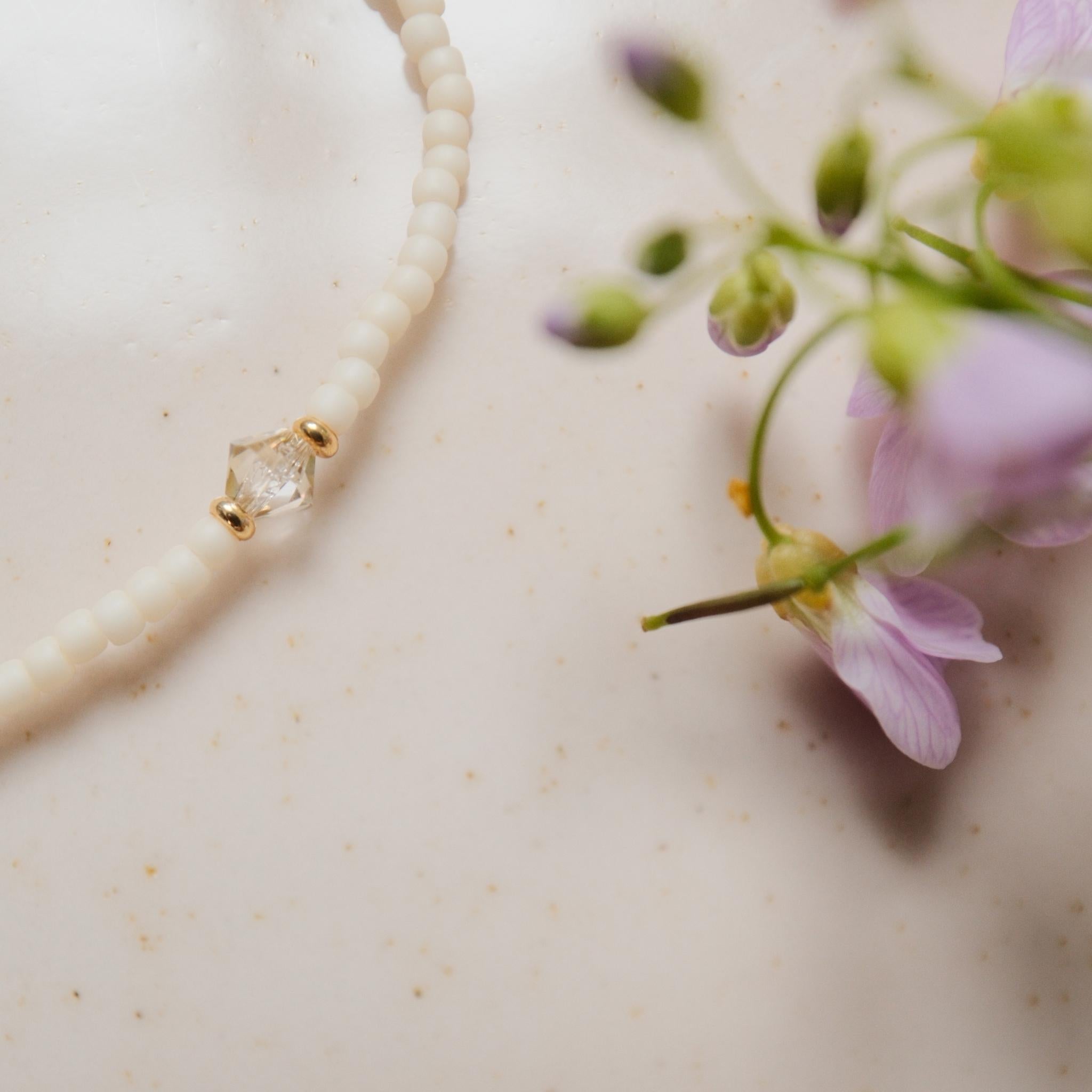 Swarovski Perle auf einem Armband neben einer lila Blume