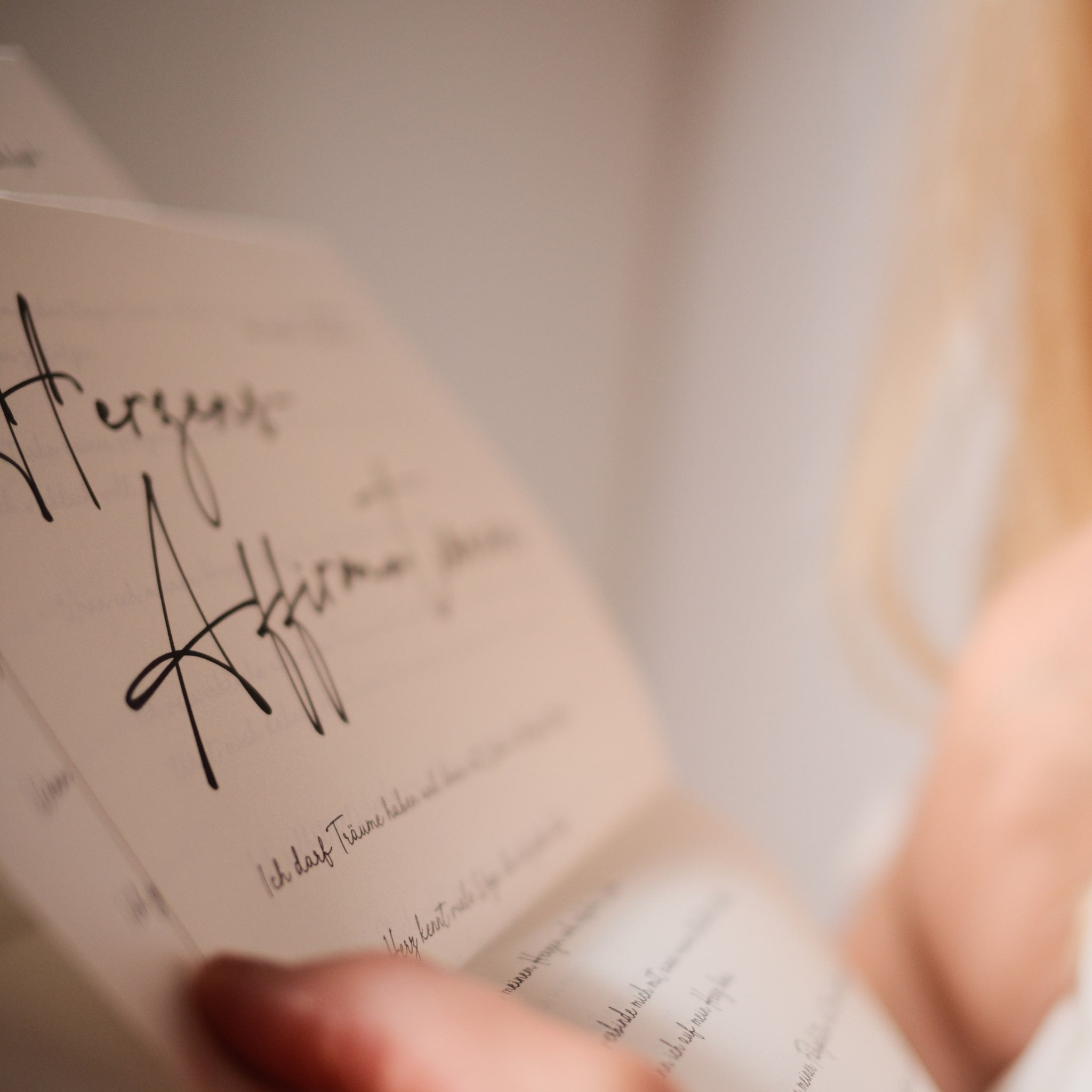 Ein Briefausschnitt mit dem Schriftzug Herzensaffrimationen und Affirmationen darauf die eine Frau liest und sich dabei auf das Herz fasst